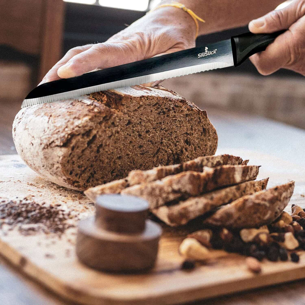 A person slicing fresh bread with a serrated knife on a wooden cutting board, highlighting kitchen organization.