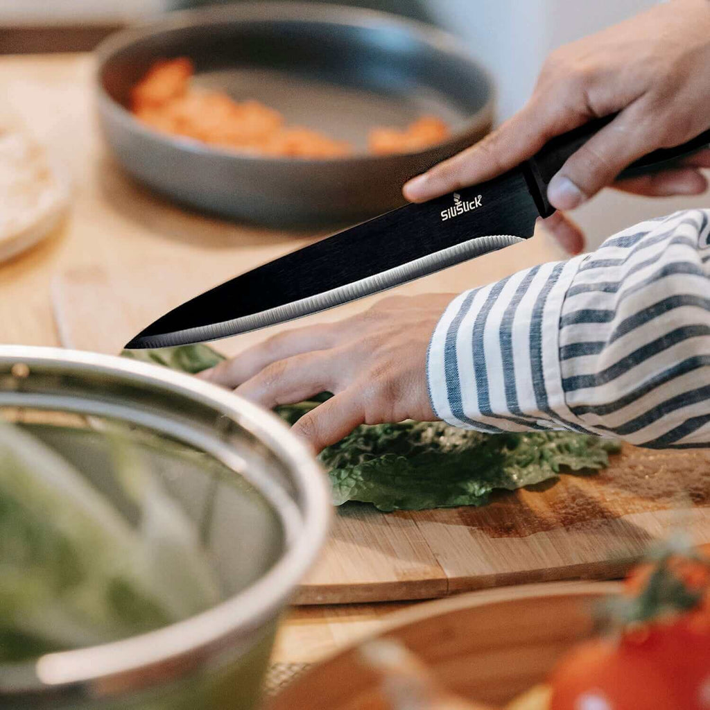 Person using a knife on a cutting board while preparing fresh vegetables in the kitchen, highlighting the Magnetic Knife Holder Strip.